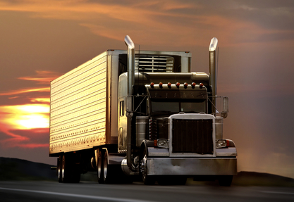 Big truck driving on a highway with sunset in background